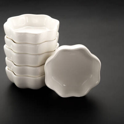 Flower shape empty ceramic dishes stack up on a black background