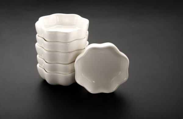 Flower shape empty ceramic dishes stack up on a black background