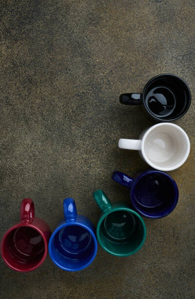 Top view of empty colored ceramic cups standing in an arc with space for text