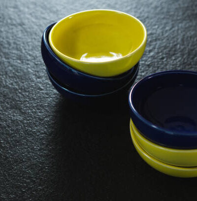 Close up of yellow and blue plastic bowl on black background